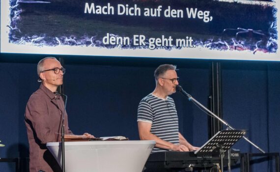Andreas Riedel am Rednerpult und MicWen am Keyboard