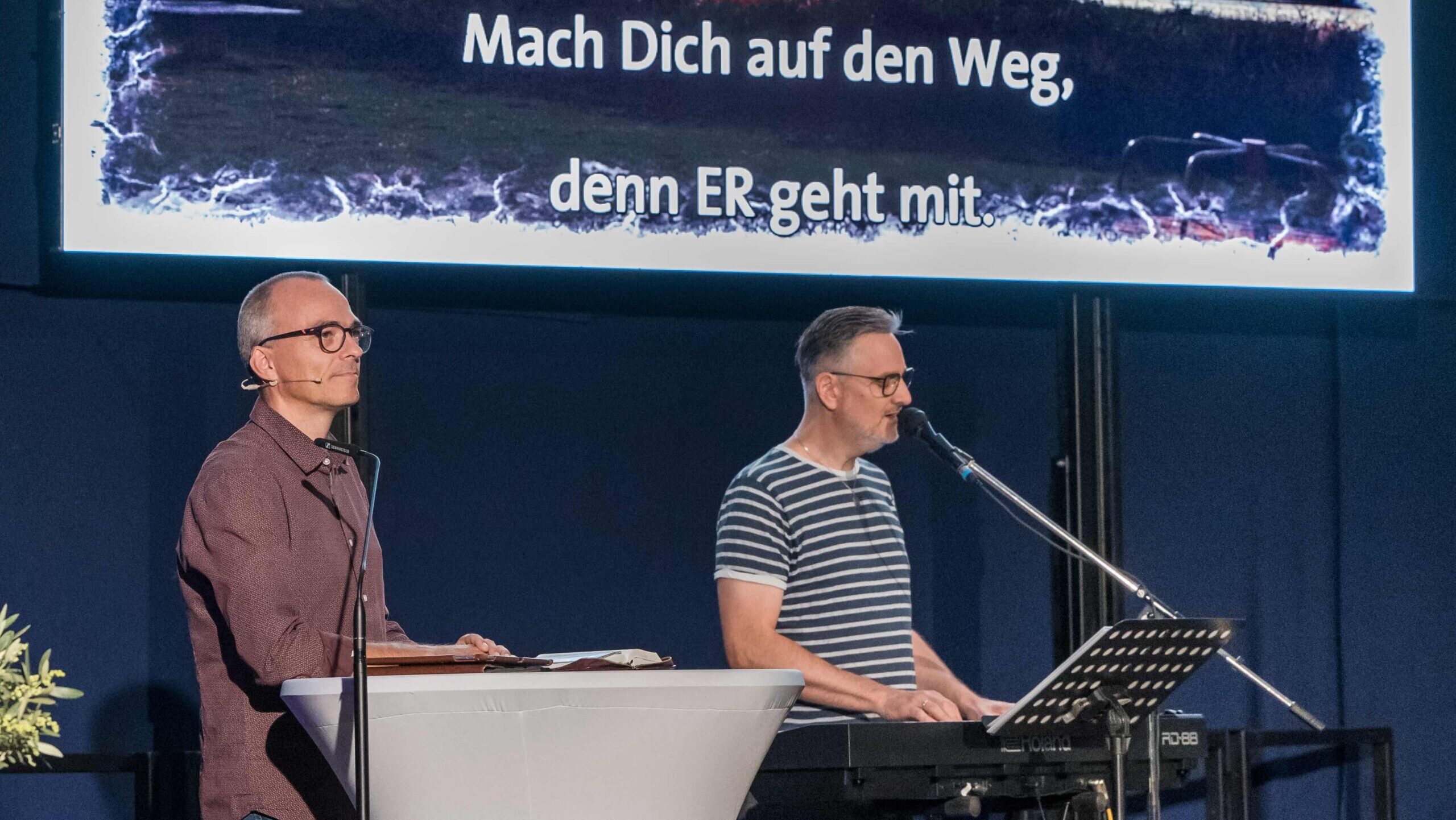 Andreas Riedel am Rednerpult und MicWen am Keyboard